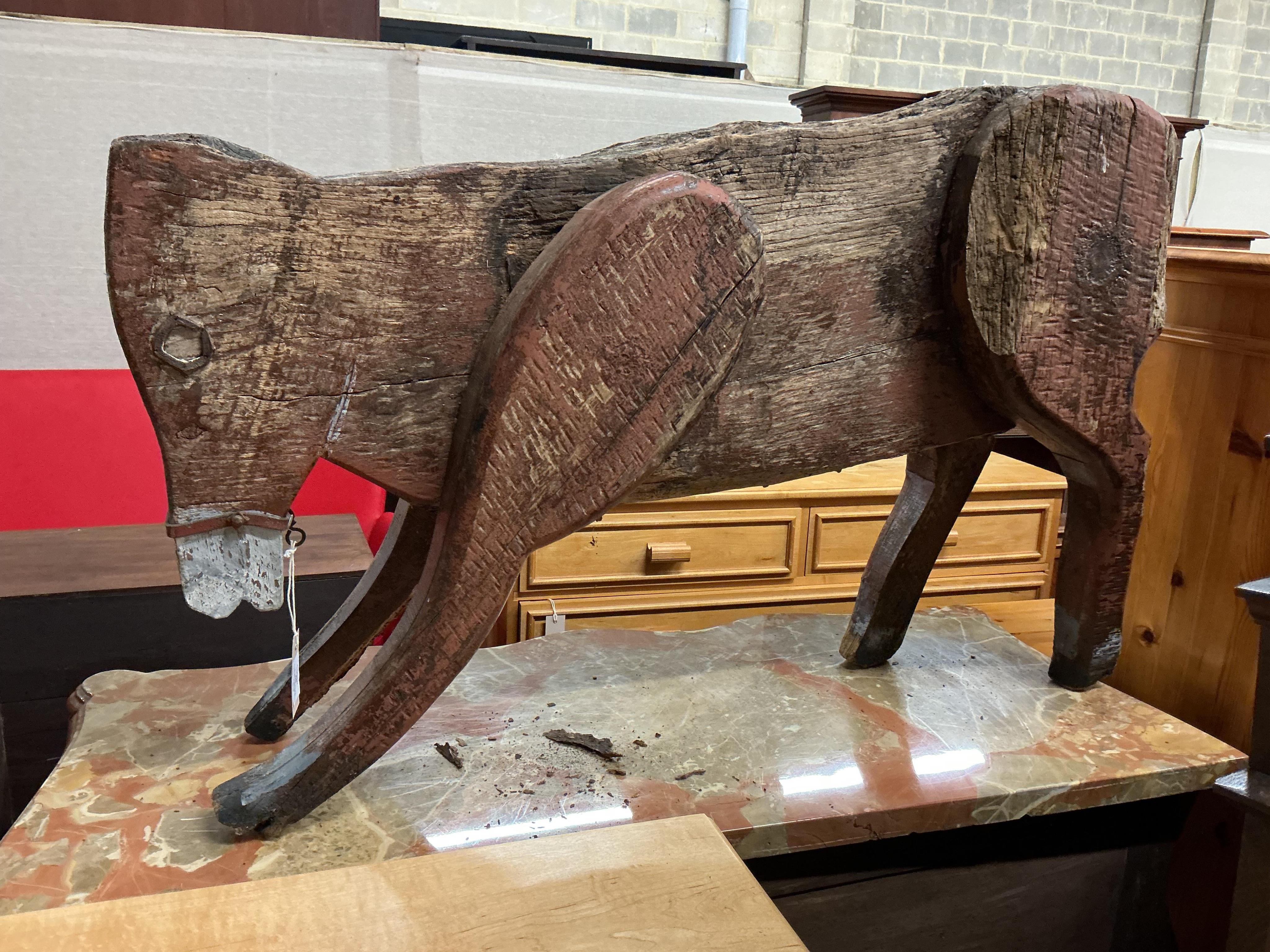 A 19th century primitive painted wood model of a cow with articulated limbs, length 100cm, height 62cm